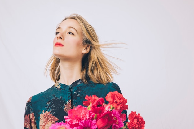 Attraente donna sognante con bouquet di fiori