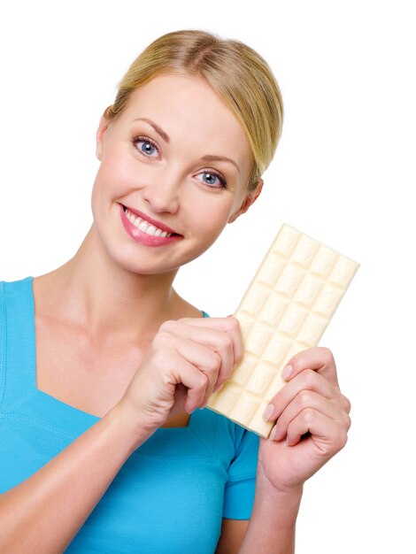 Attraente donna sorridente felice che tiene la barra di cioccolato bianco dolce - isolato su bianco. Copia spazio