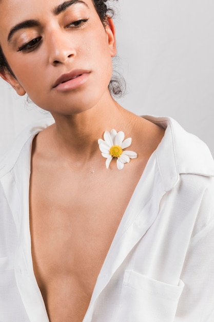 Attraente donna triste con fiore vicino al collo