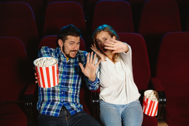 Attraente giovane coppia caucasica guardando un film in un cinema, casa o cinema. Guarda espressivo, stupito ed emotivo. Seduto da solo e divertendomi. Relazione, amore, famiglia, tempo del fine settimana.