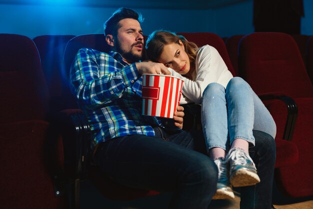 Attraente giovane coppia caucasica guardando un film in un cinema, casa o cinema. Guarda espressivo, stupito ed emotivo. Seduto da solo e divertendomi. Relazione, amore, famiglia, tempo del fine settimana.