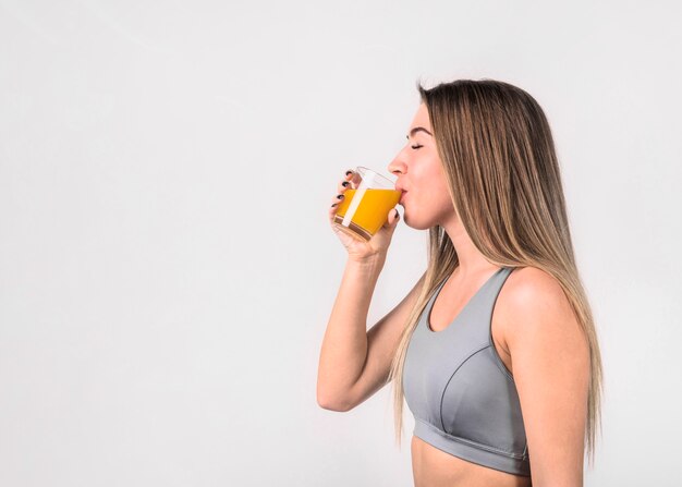 Attraente giovane donna in abbigliamento sportivo bere succo