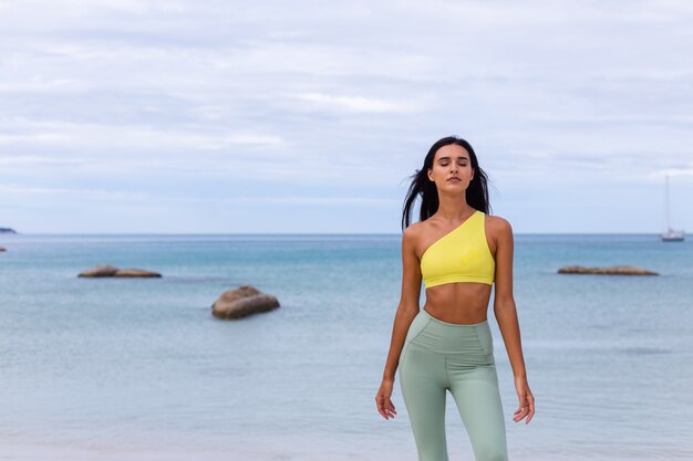 Attraente giovane donna in abbigliamento sportivo colorato sulla spiaggia