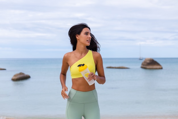 Attraente giovane donna in abbigliamento sportivo colorato sulla spiaggia