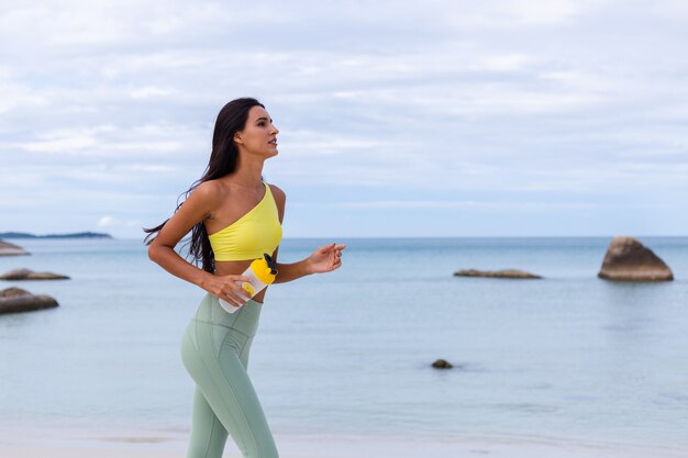 Attraente giovane donna in abbigliamento sportivo colorato sulla spiaggia