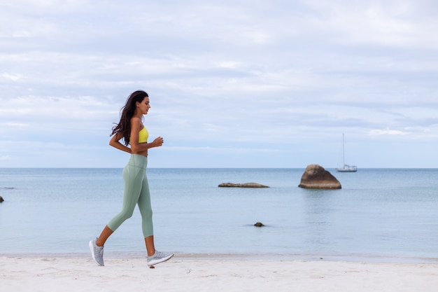 Attraente giovane donna in abbigliamento sportivo colorato sulla spiaggia