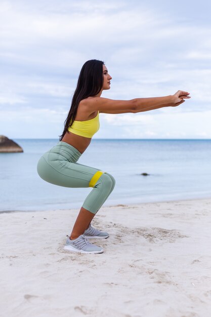 Attraente giovane donna in abbigliamento sportivo colorato sulla spiaggia