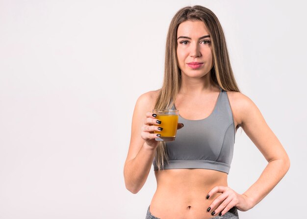 Attraente giovane donna in abiti sportivi con un bicchiere di succo