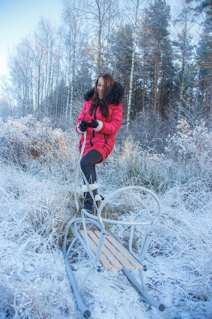 Attraente giovane donna in cappotto rosa in posa nella foresta ghiacciata.