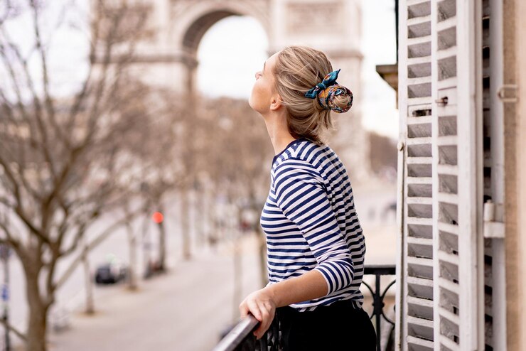 Foto gratuito attraente giovane donna sul balcone al mattino nella città di parigi. veduta dell'arco trionfale.