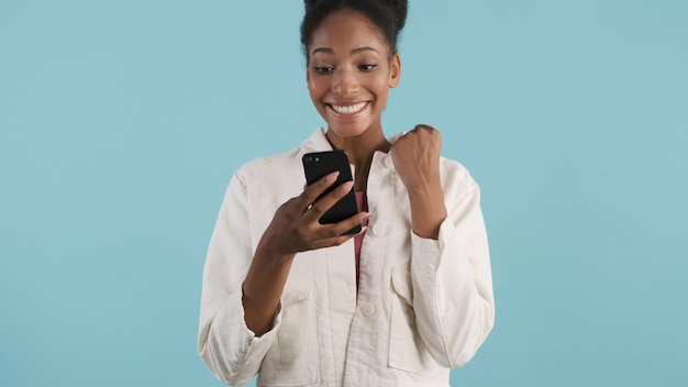 Attraente ragazza afroamericana allegra felicemente utilizzando smartphone e gioendo sulla fotocamera su sfondo colorato