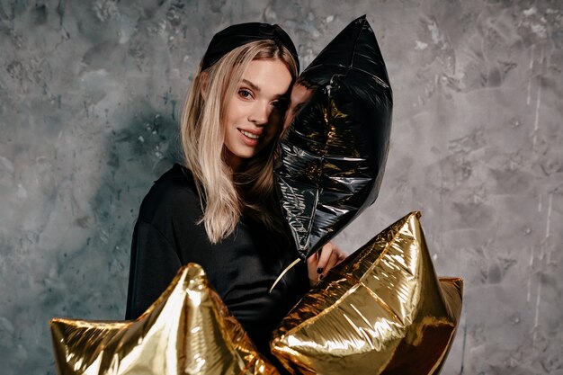 Attraente ragazza alla moda con capelli biondi vestiti di neri vestiti preparando per la festa di Natale