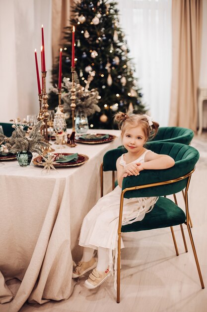 Attraente ragazza caucasica in bel vestito in cucina vicino all'albero di Natale e sorrisi