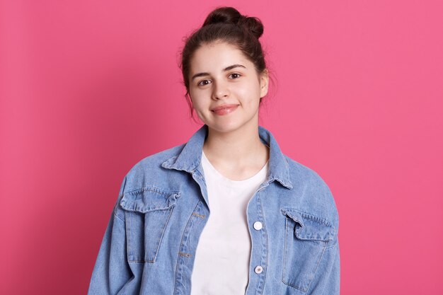 Attraente ragazza caucasica vestita casual giacca di jeans e camicia bianca, ha un panino per capelli