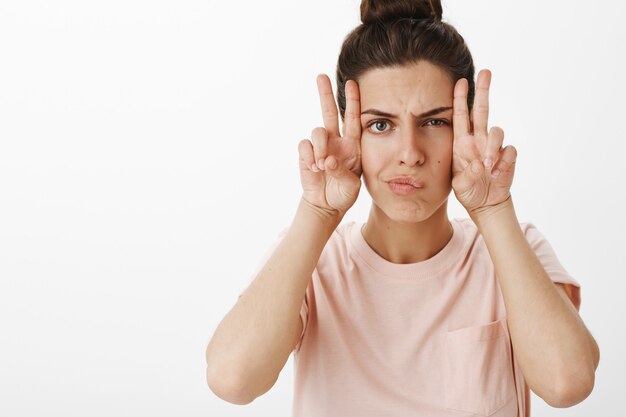 Attraente ragazza impertinente in posa contro il muro bianco