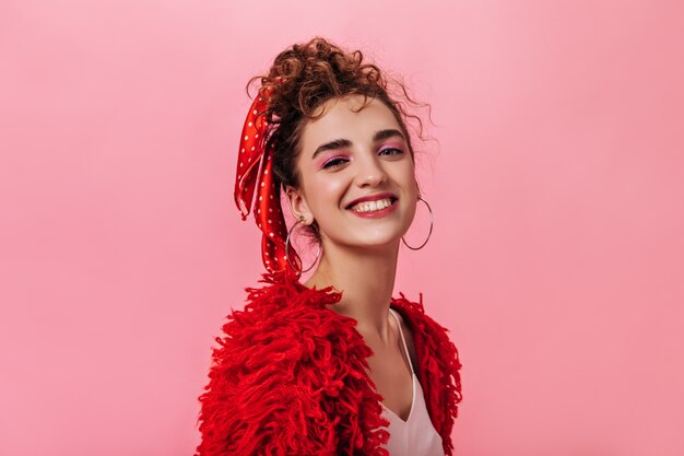 Attraente ragazza in maglione rosso sorridente sul rosa