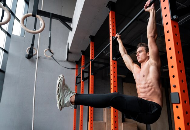 Attraente uomo in forma che si allena al chiuso in palestra