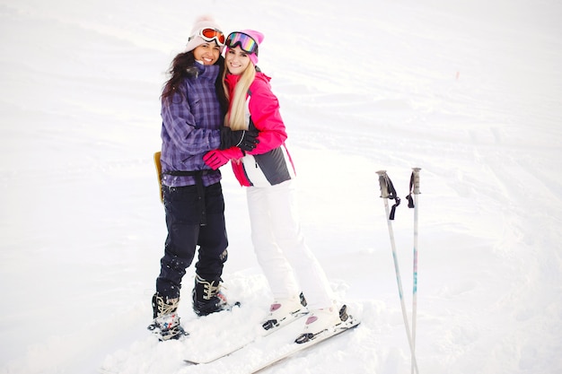 Attrezzatura da sci nelle mani delle ragazze. Colori vivaci sui vestiti da sci. Le ragazze si divertono insieme.