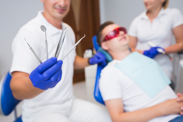 Attrezzatura sfocata della tenuta del dentista con il paziente