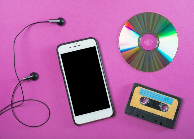 Auricolare; cellulare; compact disc e cassetta su sfondo viola