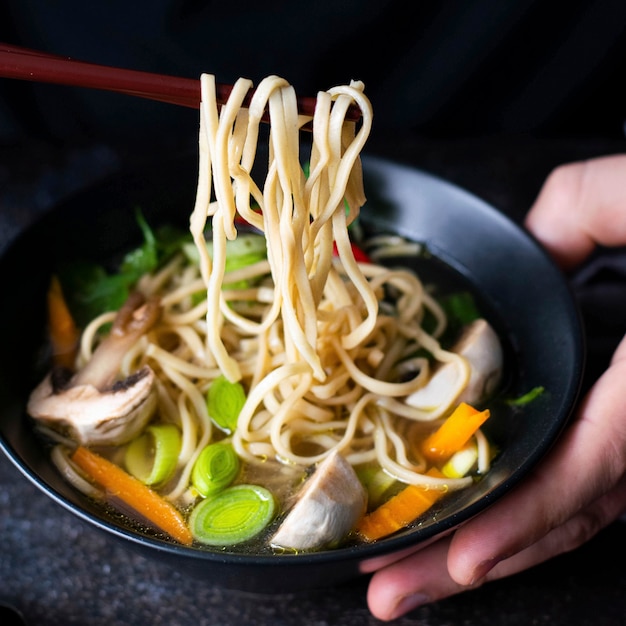Autentica zuppa di noodles asiatica in una ciotola nera