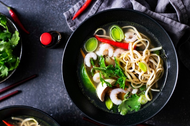 Autentica zuppa di noodles asiatica in una ciotola nera