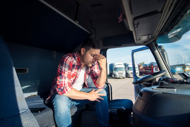 Autista del camion seduto nella sua cabina del camion si sente preoccupato e sconvolto