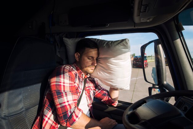 Autista di camion che dorme nella cabina del suo camion a causa della guida su lunghe distanze e del superlavoro