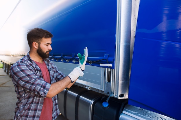 Autista di camion che indossa i guanti per rimuovere il telone del veicolo per lo scarico