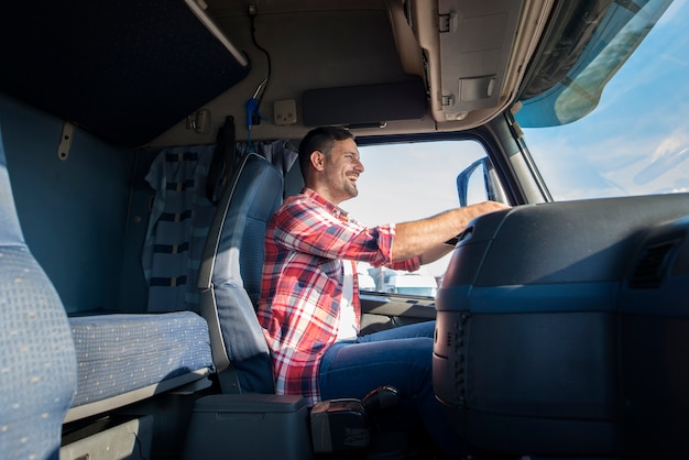 Autista di camion di mezza età professionale felice in abiti casual che guida camion sull'autostrada