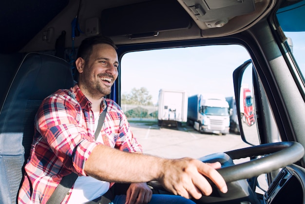 Autista di camion di mezza età professionista in abiti casual alla guida di camion e consegna merci a destinazione