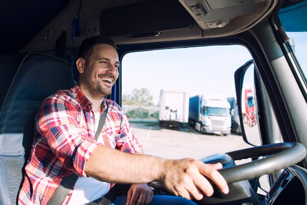 Autista di camion di mezza età professionista in abiti casual alla guida di camion e consegna merci a destinazione