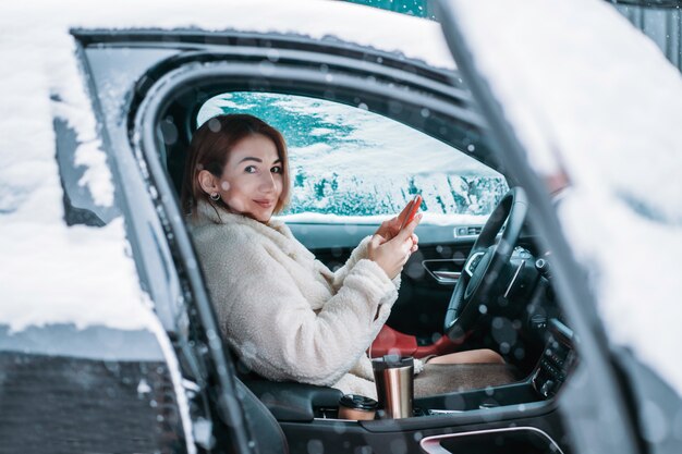 Autista donna attraente nsitting dietro il volante nella sua auto