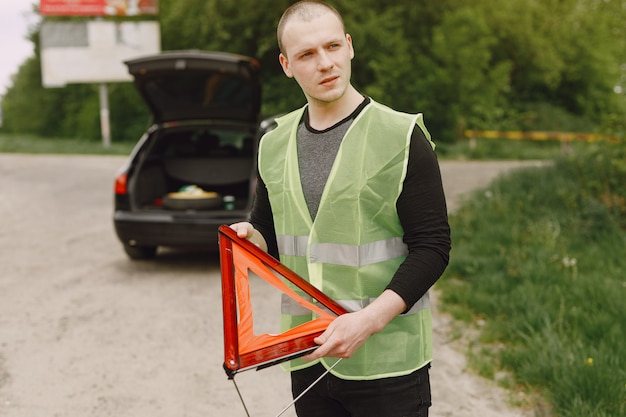 Auto con problemi e un triangolo rosso per avvisare gli altri utenti della strada