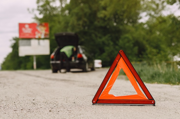 Auto con problemi e un triangolo rosso per avvisare gli altri utenti della strada