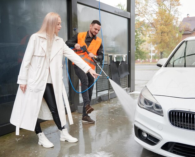 Auto lavavetri maschio che pulisce l'auto sotto la supervisione del proprietario