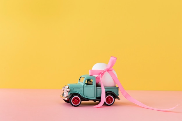 Automobile di Pasqua con uovo bianco e nastro rosa