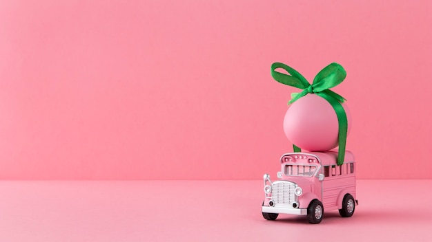 Automobile di Pasqua rosa con uovo rosa e nastro verde