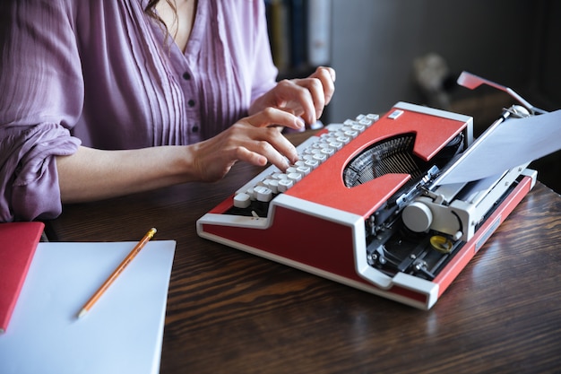 Autore seduto al tavolo e digitando su typerwriter al chiuso