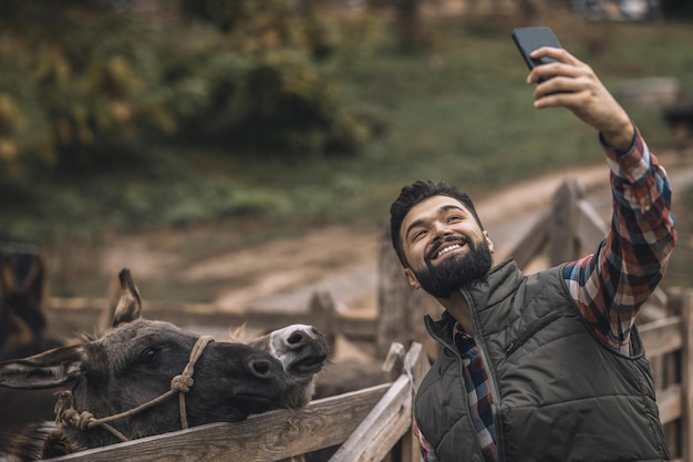 Autoscatto. Contadino allegro che fa selfie con gli asini