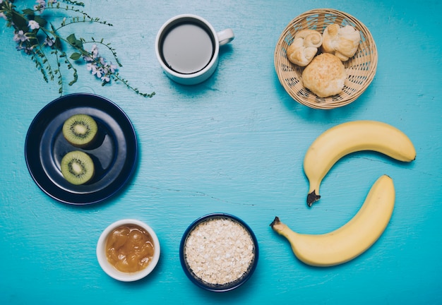 Avena; Banana; Kiwi; marmellata; tazza di caffè e pane su priorità bassa strutturata blu