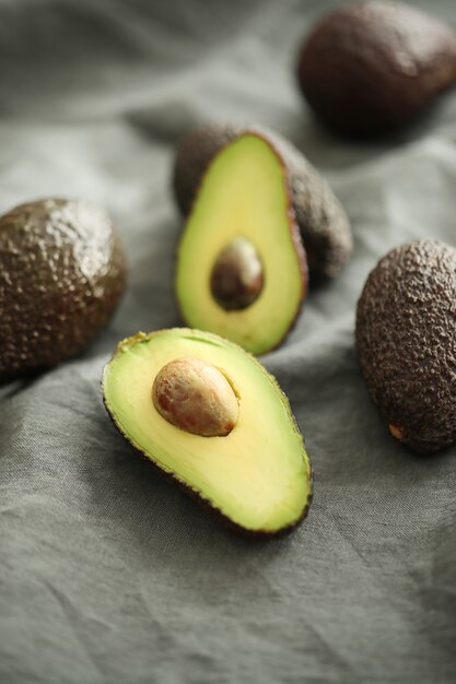 Avocado interi e tagliati su panno grigio