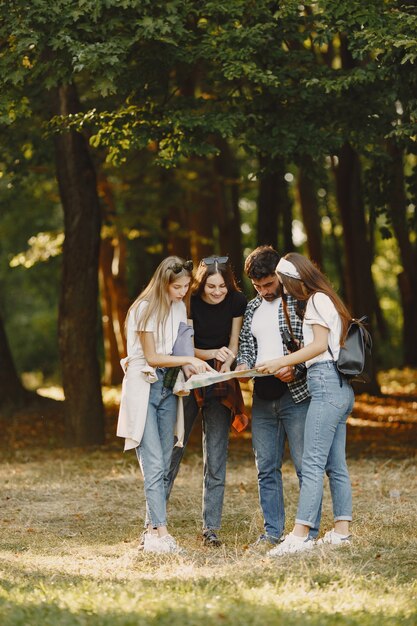 Avventura, viaggi, turismo, escursione e concetto di persone. Gruppo di amici sorridenti in una foresta. Uomo con il binocolo.