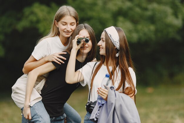 Avventura, viaggi, turismo, escursione e concetto di persone. Tre ragazze in una foresta.