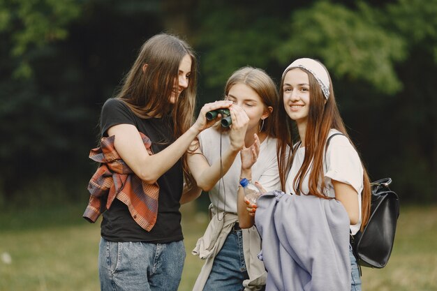 Avventura, viaggi, turismo, escursione e concetto di persone. Tre ragazze in una foresta.