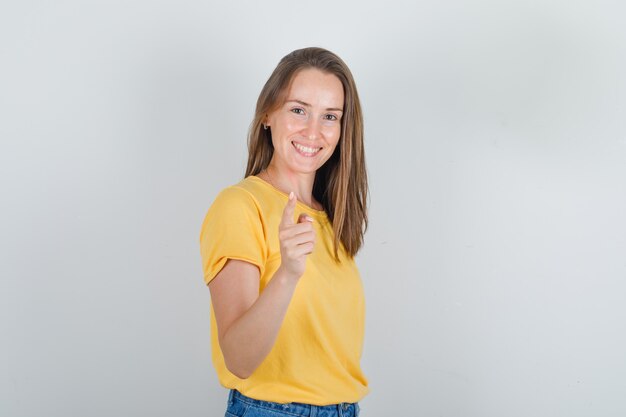 Avvertimento della giovane donna con il dito per divertimento in maglietta gialla e che sembra allegro
