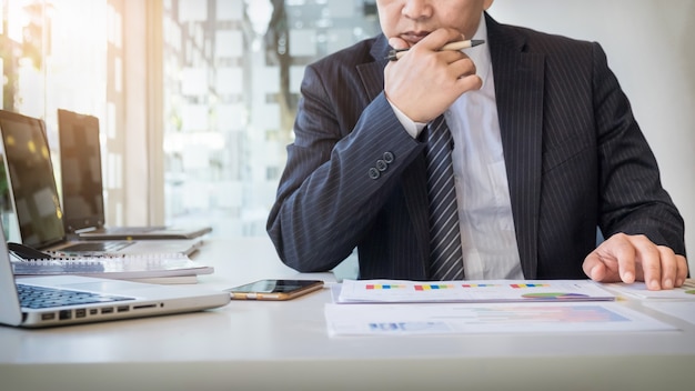 Avvio del processo di lavoro. Uomo d&#39;affari che lavora al tavolo di legno con il nuovo progetto di finanza. Notebook moderno sul tavolo. Punta di mano della penna