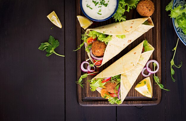 Avvolgere la tortilla con falafel e insalata fresca. Tacos Vegani. Cibo vegetariano sano. Vista dall'alto