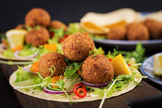 Avvolgere la tortilla con falafel e insalata fresca. Tacos Vegani. Cibo vegetariano sano.