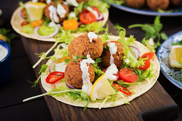 Avvolgere la tortilla con falafel e insalata fresca. Tacos Vegani. Cibo vegetariano sano.